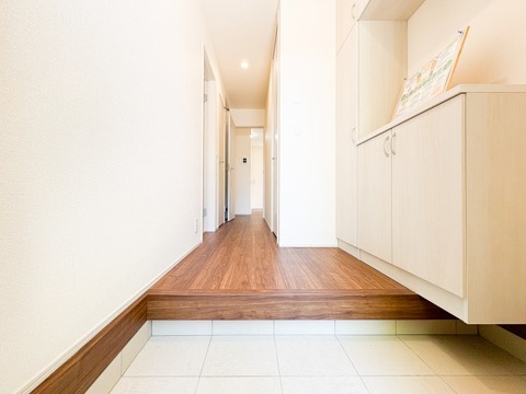 質感豊かな木目調のフローリングと、明るいホワイトの建具が調和した心地よい空間。フロートタイプのシューズボックスが足元に広がりをもたらし、玄関をより広く、スタイリッシュに演出する洗練された邸宅です。