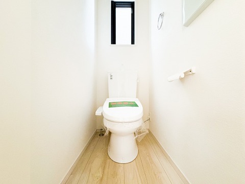 白を基調とした、清潔感あふれるトイレ空間。スリット窓から自然光が差し込み、明るく爽やかな印象を与えます。温水洗浄便座付きで、毎日を快適に過ごせる機能性もしっかりと備わっています。