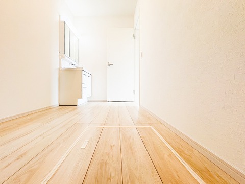 白を基調とした清潔感あふれる洗面室。三面鏡タイプの洗面化粧台は、鏡裏に小物を収納でき、忙しい朝の身支度もスムーズに整います。明るい木目のフローリングが、空間に優しく柔らかな印象をプラスします。