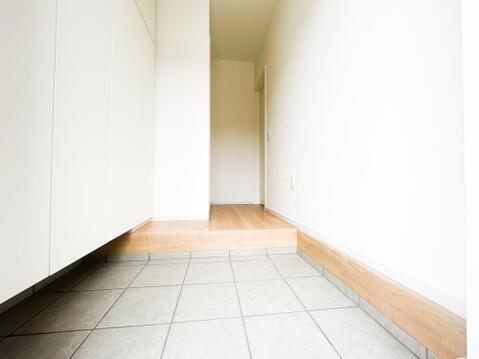 白を基調とした壁面と明るい木目の框(かまち)が、爽やかで清潔感のある空間を演出する玄関。グレー調の上品な床タイルは泥汚れなどが目立ちにくく、お掃除も楽々。すっきりと洗練された住まいの顔です。