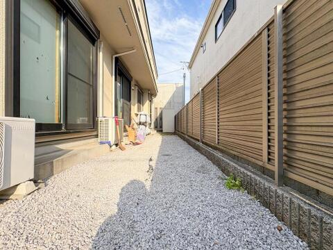 砂利敷きで手入れがしやすい、隣家との間の通路です。明るい陽光が差し込み、風通しも良好。プライベートな空間を確保し、すっきりとした印象を保ちます。