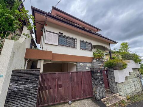 落ち着いた色合いの外観が印象的な戸建てです。プライバシーに配慮されたアプローチと駐車スペースが、家族の安心とゆとりのある暮らしを演出します。