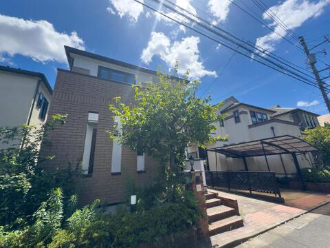 青空が広がる開放的なロケーション。煉瓦調の温かみある外観と緑豊かなアプローチが、家族の毎日を彩ります。