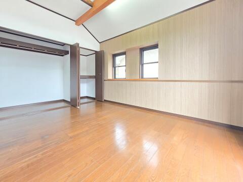 勾配天井と見せ梁が室内に開放感をもたらす洋室です。横並びの窓から自然光が入り、2か所のクローゼットも備えています。衣類や季節物を分けて収納でき、居住スペースを広く使いやすい一室です。