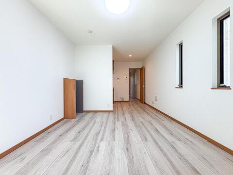 明るい陽光が差し込む、開放感あふれる室内。白い壁と温かみのある木目調フローリングが、家族の穏やかな時間を育みます。お子様ものびのびと過ごせる広々とした空間です。