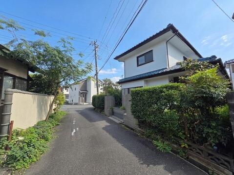 建物周辺は低層住宅が並ぶ落ち着いた街並みが広がっています。前面道路は車通りも比較的少なく、住環境の穏やかさを感じられます。緑のある住宅が点在し、日々の暮らしをゆったりと送れる周辺環境です。