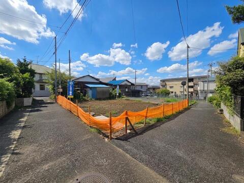 敷地全体を正面から捉えた現地写真です。土地面積113.20平米(34.24坪)を確保し、建物面積90.00平米の4LDKが建築予定です。敷地の広さや周辺との位置関係をご確認いただけます。