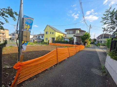道路側から敷地と周辺の街並みを見渡した現地写真です。道路沿いには戸建住宅が建ち並び、現地の接道状況や周囲の建物との位置関係を把握できます。建築前の段階で、住まいを取り巻く環境まで確認していただけます。