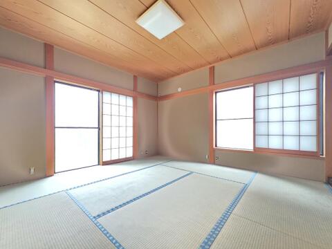 1階に設けられた8帖の和室です。二方向に窓があり、障子を通した光が畳の上に広がります。木目の天井や柱が残る落ち着いた室内で、座卓を置いてくつろいだり、布団を敷いて客間として使ったりする広さがあります。