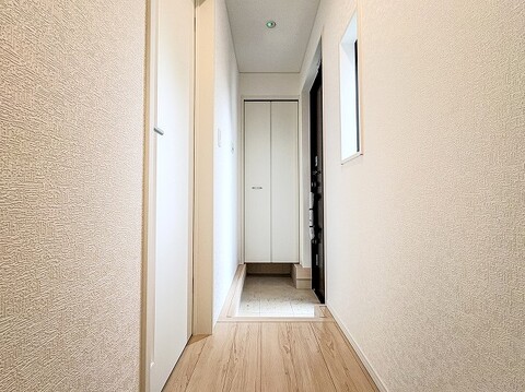 玄関から室内へとまっすぐ伸びる清潔感あふれる廊下空間。突き当たりの収納棚や明るい壁面・フローリングが開放感を出し、帰宅時も優しく温かく迎えてくれる心地よい導線デザインです。