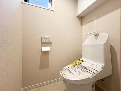 白を基調とした清潔感あふれるトイレ。手洗い一体型で使い勝手が良く、壁面のリモコン操作で見た目もスッキリ。トイレットペーパー等の保管に便利な上部収納付きです