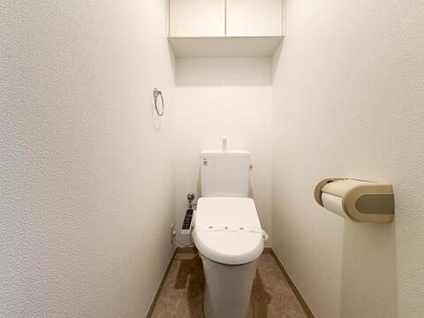 快適な温水洗浄便座付きトイレ。頭上の収納スペースもしっかり確保されており、トイレットペーパーのストックや掃除用具もスッキリ片付きます。