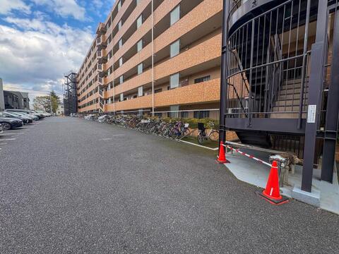 青空の下、レンガ調の外壁が美しい大規模マンション。敷地内の駐車場と駐輪場で、子育て世代の移動もスムーズ。家族の笑顔が弾む、快適な毎日をここで。
