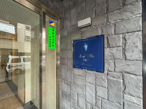 ALSOKと警察官立寄所の表示が、ご家族の毎日を優しく見守ります。石積み調の壁が迎えるエントランスは、帰宅するたびに安心感に包まれるでしょう。