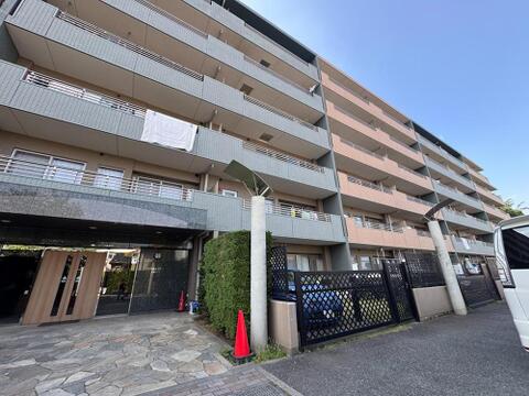 青空の下、堂々とした佇まいのマンション外観です。明るい日差しが降り注ぐバルコニーは、家族の笑顔を育む心地よい空間を提供します。