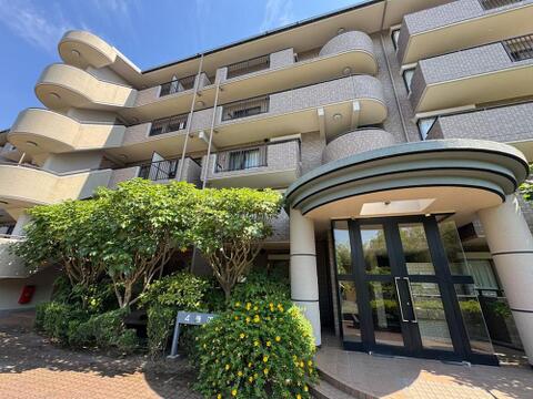 陽光が降り注ぐ明るい外観と、豊かな植栽が魅力のマンション。洗練されたエントランスが、家族の毎日を彩る安心感のある住まいです。