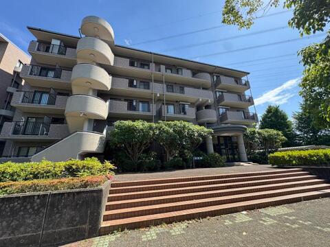 青空に映えるモダンな外観と、特徴的な螺旋階段が目を引くマンションです。豊かな植栽に囲まれ、お子様との毎日を彩る安心感のある住まい。