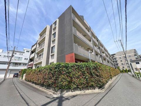 青空と豊かな緑に包まれた美しい外観。陽当り・風通しの良さを予感させる堂々たる佇まい。