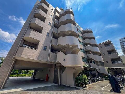 青空に映える落ち着いたブラウンタイルの佇まい。角地に堂々と佇む新耐震基準マンション