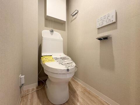 清潔感あふれる温水洗浄便座付きトイレ。上部にはトイレットペーパーなどを隠して収納できる棚も完備。