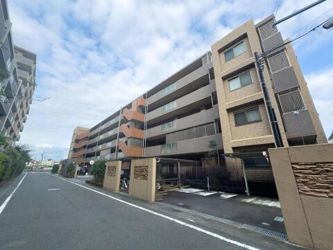 青空の下、広々とした道路に面したマンション。落ち着いた外観は、家族の穏やかな暮らしを育む住環境に溶け込み、毎日を快適にサポートします。