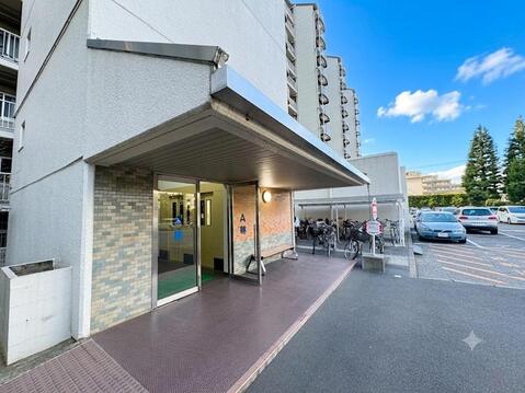 A棟エントランスは屋根付きで雨の日の出入りも快適。駐輪場を敷地内に備え、共用部は管理が行き届いた住環境です。総戸数443戸のビッグコミュニティならではの安心感があります。