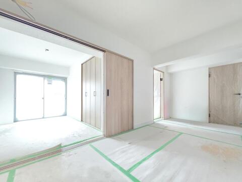 南向きの掃き出し窓から明るい陽光が差し込む洋室です。引戸を開放すれば隣接する空間と一体利用も可能。新規フルリノベーションにより建具や内装も一新され、心地よい住空間へと生まれ変わります。