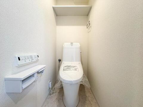 清潔感あふれるモダンなトイレ空間。温水洗浄機能付きで快適、便利な棚付きペーパーホルダーも完備し、家族みんなが気持ち良く使えます。