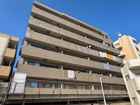 澄み切った青空の下、建物全体が明るい日差しに包まれています。バルコニーには洗濯物がなびき、家族の温かい日常が感じられる外観です。日当たり良好で快適な毎日を。