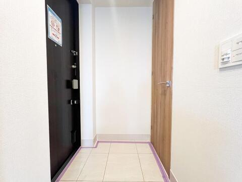 白を基調とした明るく清潔感のある玄関空間。木目調のドアが温かみを添え、足元には高級感のあるタイルを採用。人感センサー付照明付きで夜間の帰宅も安心です。