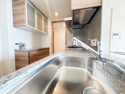 浄水器一体型水栓を備えた広々としたシンク。天然石天板や背面のカップボードなど、見た目の高級感と機能性を兼ね備えたこだわり仕様のキッチンです。