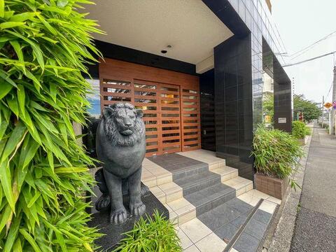 ライオン像が出迎える上質なアプローチ。高級感あふれる木目調デザインが印象的。