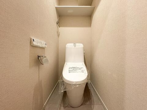快適な温水洗浄便座付きトイレ。頭上の収納スペースもしっかり確保されており、トイレットペーパーのストックや掃除用具もスッキリ片付きます。