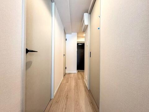 木のぬくもりを感じるナチュラルテイストのフローリングと、清潔感のある白い壁面が広がる廊下です。すっきりとしたシンプルなデザインで、居室へつながる各扉との調和が取れた美しい空間となっています。