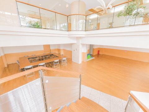 マンション敷地内に設けられた開放的な集会室スペース。吹抜け構造の開放感ある造りで、居住者同士の交流や各種集会など多目的にご活用いただける共用施設です。