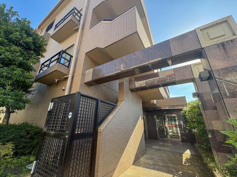 重厚な御影石のエントランスが印象的なマンション。セキュリティゲートと豊かな緑が、家族の安心と快適な毎日を優雅に演出します。