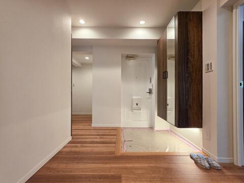 玄関には姿見付きのシューズ収納を備え、お出かけ前に全身の身だしなみを確認できます。収納の下には空間があり、足元を照らす照明も設置されています。靴をしまうことで、玄関まわりをすっきり整えられます。