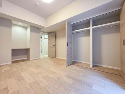 幅のあるクローゼットは内部が左右に分かれ、ご夫婦の衣類や季節ごとの洋服を分けて収納できます。上段の棚にはバッグや収納ケースも置けます。室内には照明付きカウンターもあり、身支度や作業に活用できます。