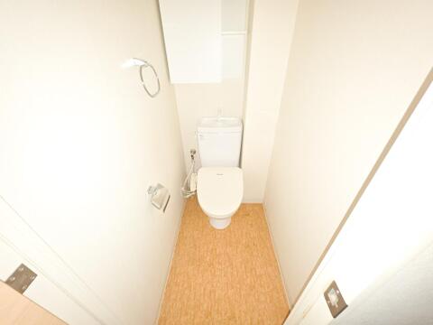 トイレは温水洗浄便座と手洗い付きタンクを備えています。背面には扉付きの収納とオープン棚があり、トイレットペーパーや掃除用品をしまいながら、小物や芳香剤なども置き場所を分けてすっきりと整えられます。
