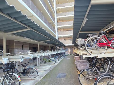 敷地内の駐輪場は屋根付きで、自転車への雨の吹き込みや直射日光を抑えます。上下2段のラックで保管場所が区分され、中央には出し入れのための通路を確保。通勤や買い物など、自転車を使う暮らしに役立ちます。
