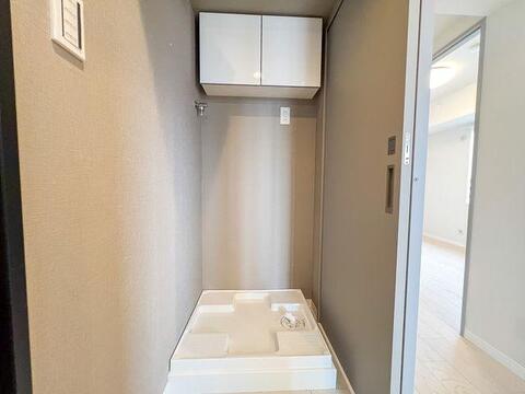 新規交換された防水パンを設置。上部には洗剤やタオルの収納に便利な吊戸棚を備えています。