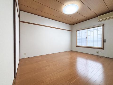 陽光差し込む明るい洋室。木目調フローリングと白壁が清潔感を演出する、心地よいプライベート空間です。