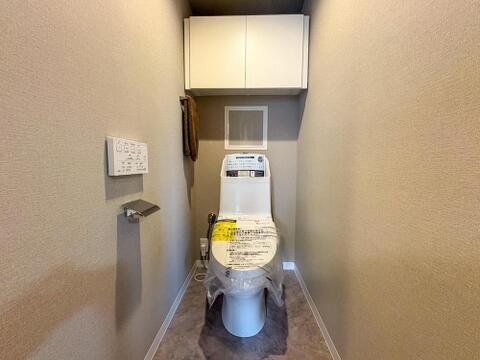 清潔感あふれる新しいトイレは、上部収納棚で空間をすっきりと保てます。家族みんなが快適に使える、機能的で落ち着いたプライベート空間です。