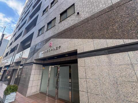 空の青さに映える、洗練されたデザインのマンション外観。重厚感あふれるエントランスが、ご家族の毎日を優雅に彩り、安心感を与えます。