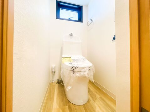 空間に心地よい自然光と爽やかな風を届ける、便利な小窓付きのトイレ。清潔感あるホワイトのクロスに、温かみのある木目フローリングが美しく調和しています。毎日を快適に過ごせる温水洗浄便座仕様です。