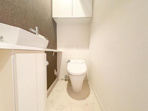 清潔感あふれるトイレは、上部収納と手洗いシンク付きで機能的。アクセントクロスがおしゃれな雰囲気を演出し、快適な毎日をサポートします。
