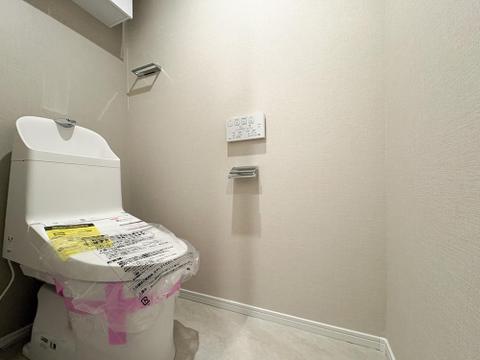 清潔感あふれる温水洗浄便座付きトイレ。手洗い一体型で節水性も高く、吊戸棚付きで収納力も確保。