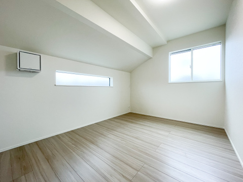 屋根の形状を活かした勾配天井が、お部屋に独特の開放感と個性を与えています。スタイリッシュな横長窓からは柔らかな光が差し込み、日中も穏やかな雰囲気。