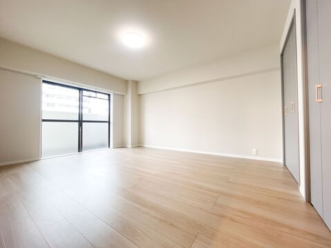 大きな掃き出し窓から心地よい光が差し込む、明るく広々とした寝室。落ち着いたトーンの建具とナチュラルな床材が、安らぎの時間を演出します。十分な広さがあるため、大型のベッドもゆとりを持って配置可能です。