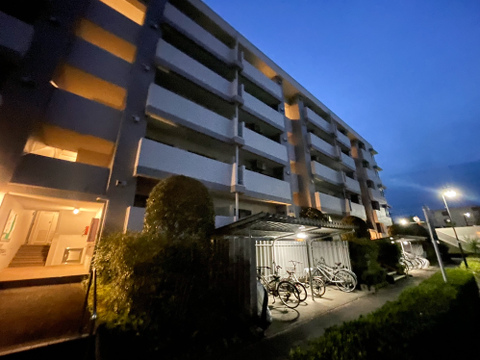 夕暮れ時のグラデーションに、マンションの窓明かりが灯り始める光景。どこか懐かしく、温かい気持ちになる一枚です。整然と並ぶベランダや駐輪場の生活感に、今日も一日が終わる安らぎを感じます。(94文字)
